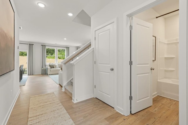 hallway with light wood-type flooring, stairway, baseboards, and recessed lighting