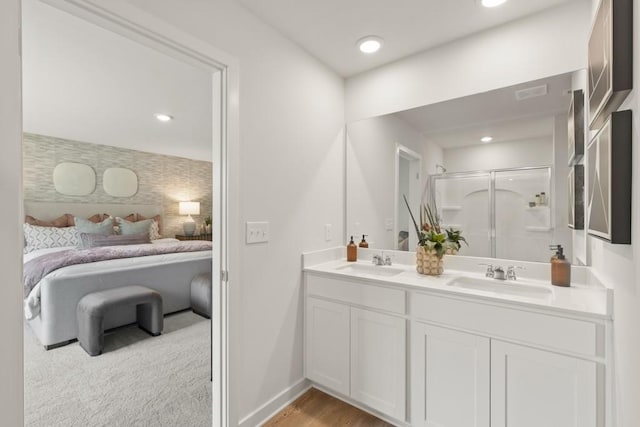 ensuite bathroom with double vanity, ensuite bath, a sink, and a shower stall