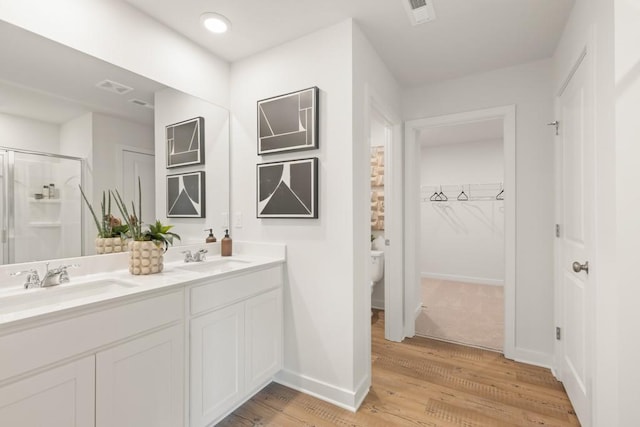 bathroom with double vanity, wood finished floors, a sink, and toilet