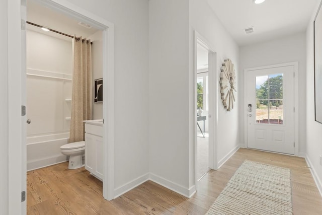 foyer entrance featuring light wood-style flooring, visible vents, and baseboards