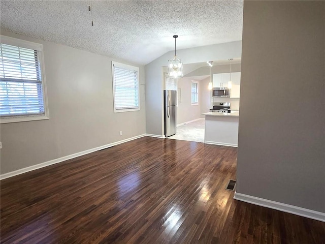 unfurnished dining area with lofted ceiling, dark wood-style floors, baseboards, and a textured ceiling