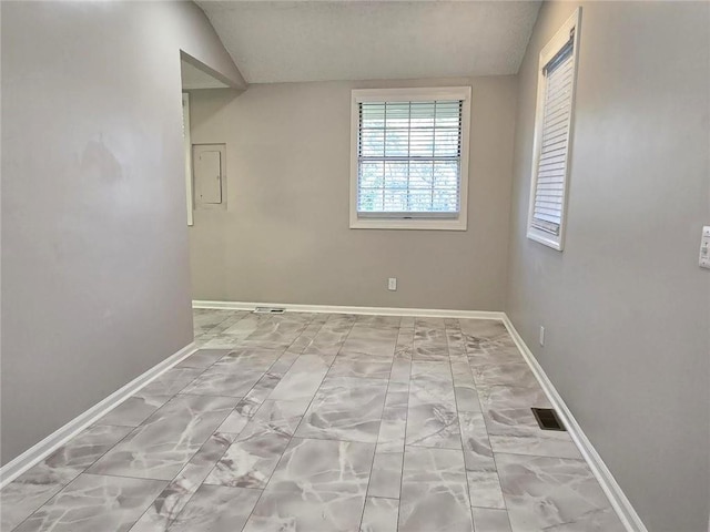 unfurnished room featuring lofted ceiling, electric panel, visible vents, and baseboards