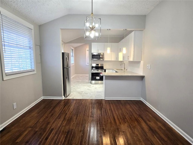 kitchen featuring a sink, appliances with stainless steel finishes, light wood finished floors, lofted ceiling, and light countertops