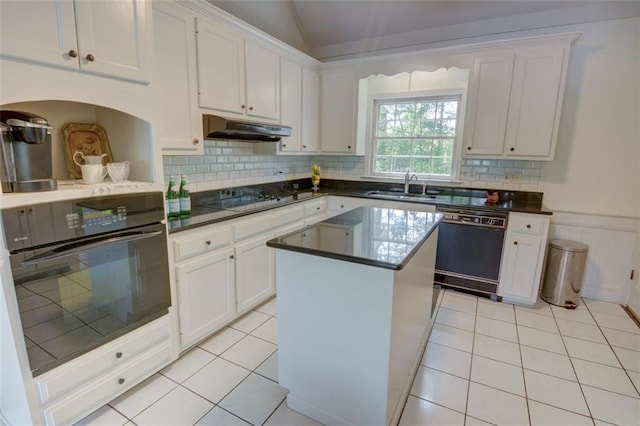 kitchen featuring black appliances, under cabinet range hood, white cabinets, a sink, and wainscoting