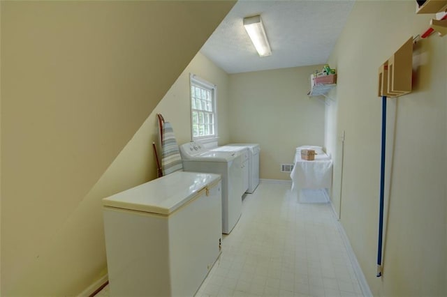washroom featuring independent washer and dryer, a textured ceiling, baseboards, and light flooring
