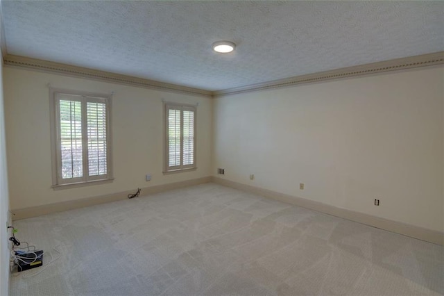empty room featuring light colored carpet, a textured ceiling, baseboards, and ornamental molding