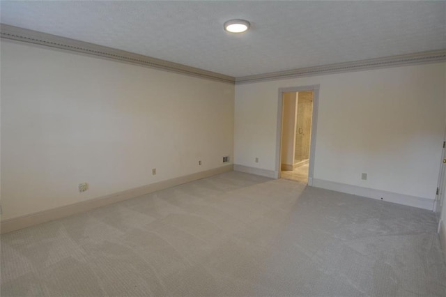 empty room with light colored carpet, ornamental molding, and baseboards