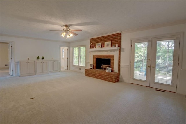 unfurnished living room with light carpet, crown molding, ceiling fan, plenty of natural light, and a brick fireplace