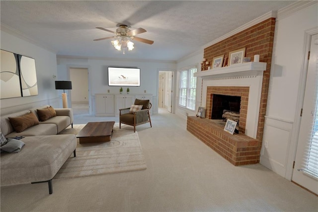 living area with ceiling fan, crown molding, carpet, a brick fireplace, and a textured ceiling