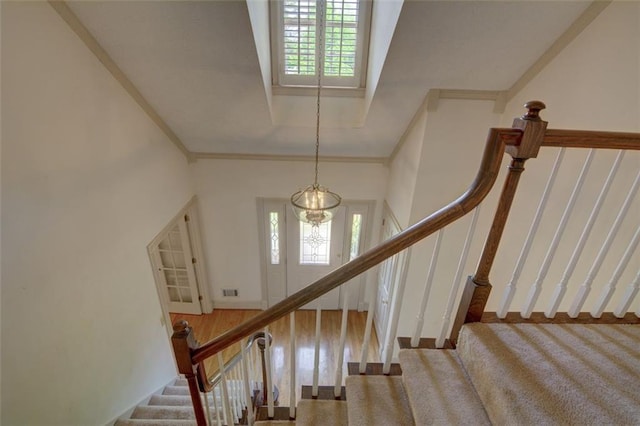 staircase with plenty of natural light, carpet floors, and crown molding