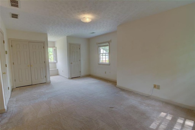 unfurnished bedroom with light colored carpet, baseboards, and a textured ceiling