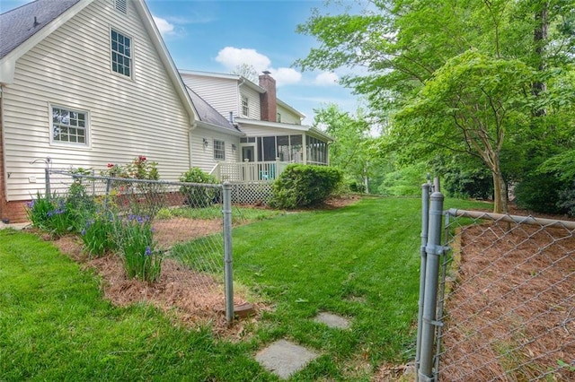 rear view of house with a sunroom, a chimney, roof with shingles, and a gate