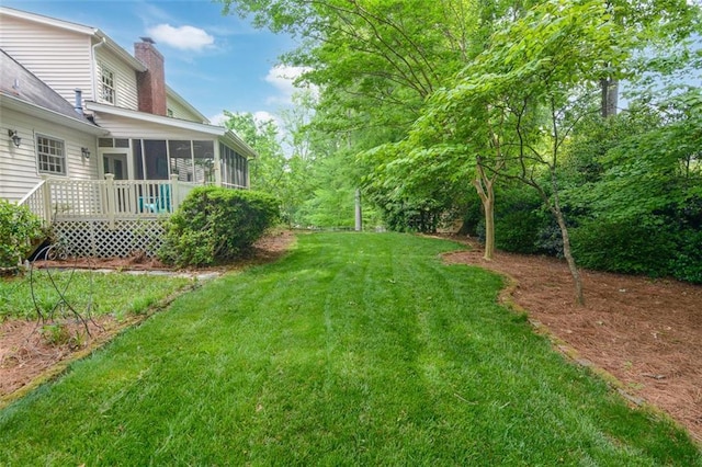 view of grassy yard with a sunroom
