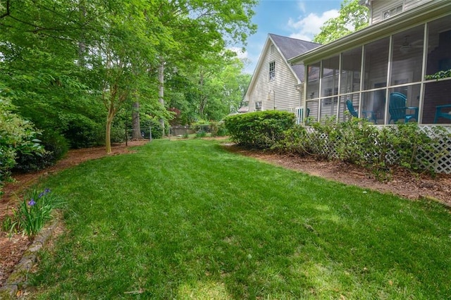 view of green lawn with a sunroom