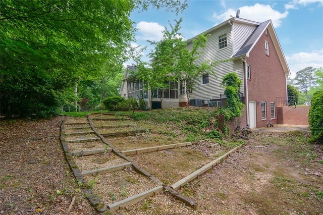 rear view of property with a sunroom, a vegetable garden, and brick siding