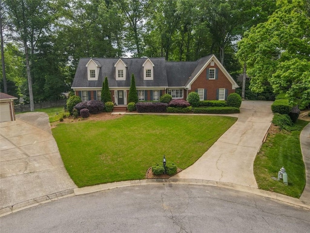 cape cod-style house featuring driveway, brick siding, and view of scattered trees