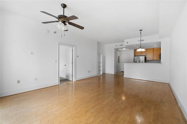 unfurnished living room with ceiling fan with notable chandelier and hardwood / wood-style floors