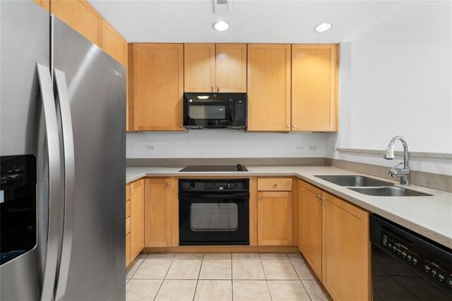 kitchen featuring light tile patterned flooring, light brown cabinetry, sink, and black appliances