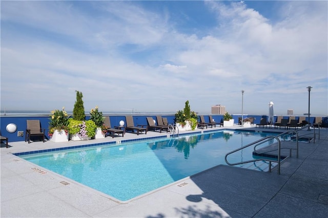 view of swimming pool with a patio and a water view