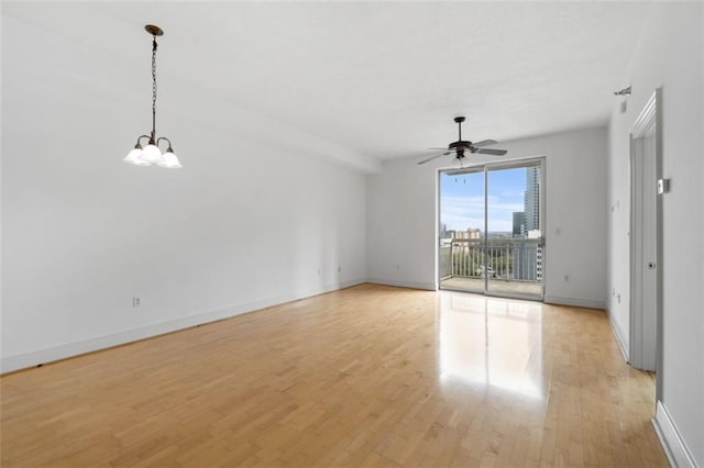 unfurnished living room featuring ceiling fan with notable chandelier and light wood-type flooring