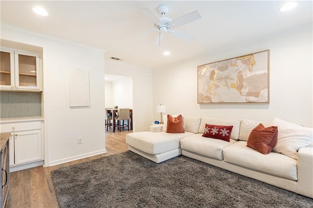 living room featuring ceiling fan, recessed lighting, wood finished floors, visible vents, and ornamental molding