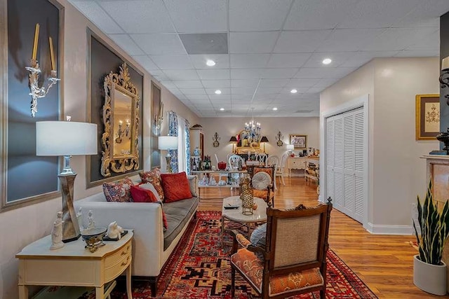 living room with a paneled ceiling and light hardwood / wood-style floors