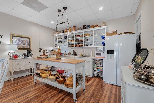 kitchen featuring pendant lighting, white appliances, white cabinetry, a paneled ceiling, and dark wood-type flooring