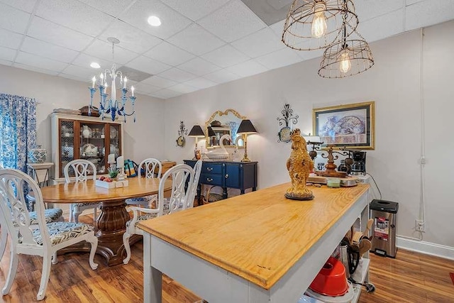 dining space with light hardwood / wood-style flooring, a chandelier, and a paneled ceiling