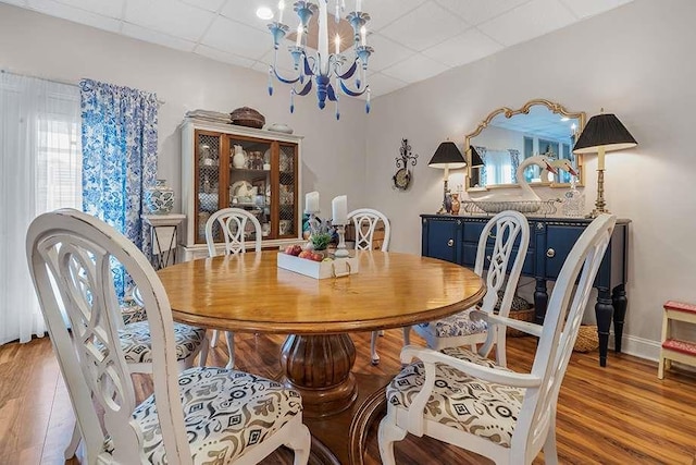 dining area featuring an inviting chandelier, a paneled ceiling, and light hardwood / wood-style flooring