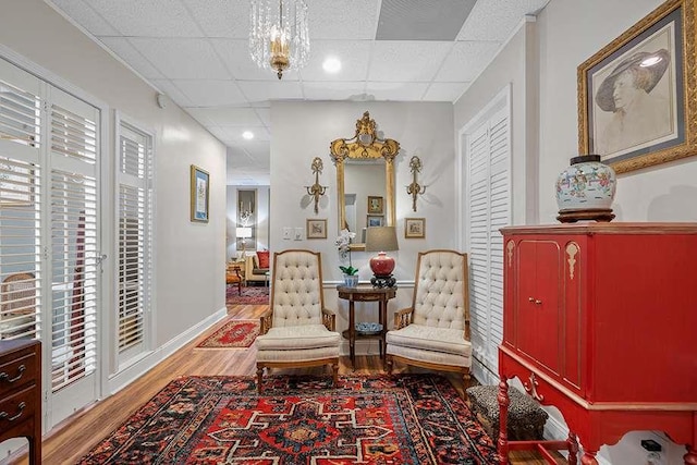 living area featuring a paneled ceiling, a wealth of natural light, and hardwood / wood-style flooring