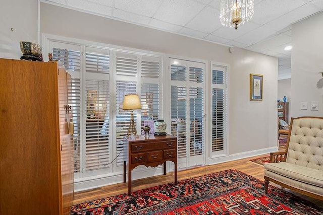 sitting room with a paneled ceiling, a notable chandelier, and hardwood / wood-style flooring