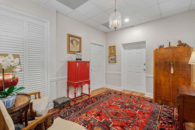 foyer entrance featuring a paneled ceiling, hardwood / wood-style floors, and a notable chandelier