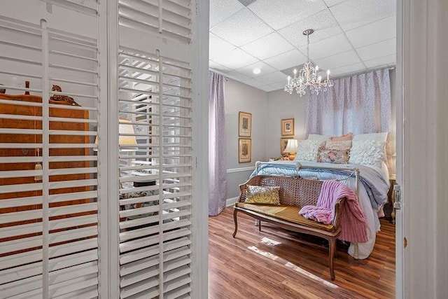 bedroom with a paneled ceiling, a chandelier, and hardwood / wood-style flooring