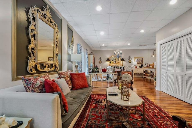 living room with a paneled ceiling, a notable chandelier, and hardwood / wood-style floors