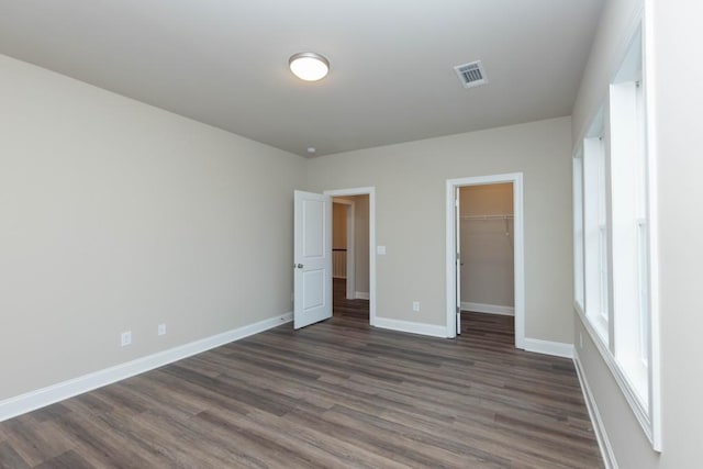5587 Spring St, Flowery Branch, GA 30542 - unfurnished bedroom with visible vents, dark wood finished floors, baseboards, a closet, and a spacious closet