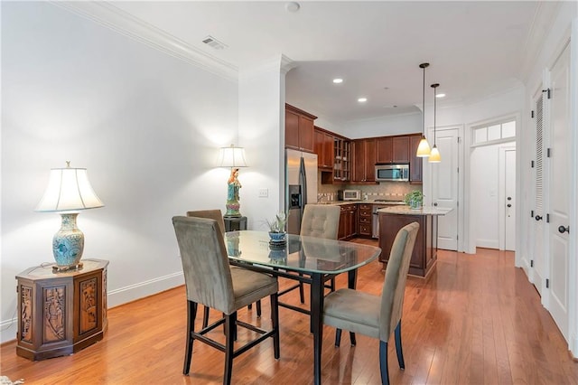 dining area with crown molding and light wood-type flooring