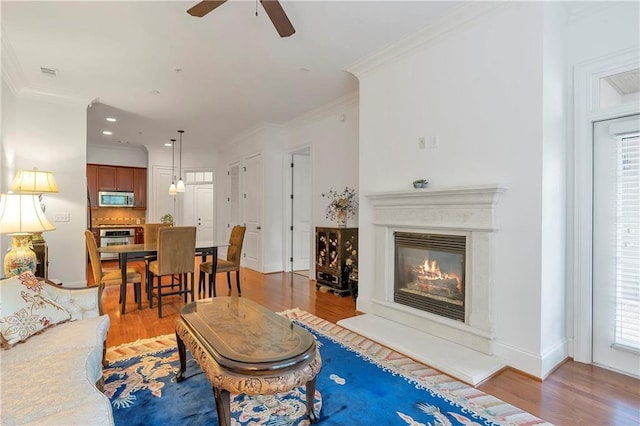 living room with ceiling fan, hardwood / wood-style flooring, and ornamental molding