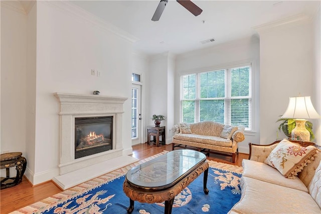 living room with hardwood / wood-style floors, ceiling fan, and crown molding