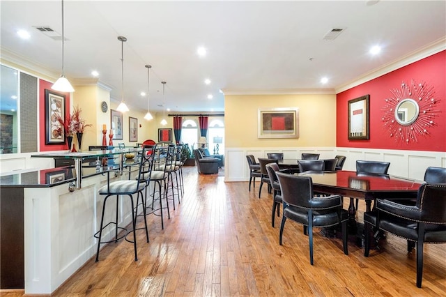 dining space with light hardwood / wood-style floors and crown molding