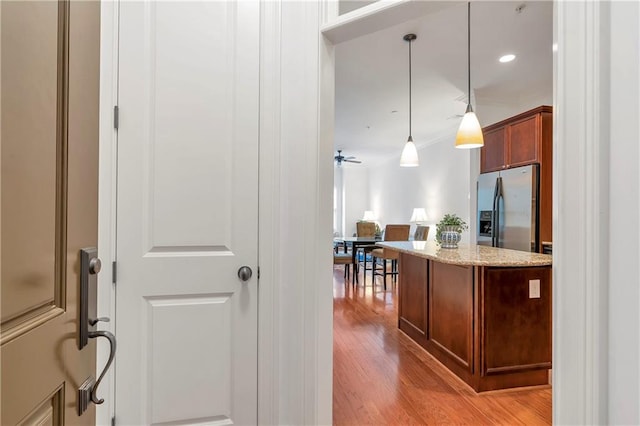 kitchen with light stone counters, ceiling fan, light wood-type flooring, decorative light fixtures, and stainless steel refrigerator with ice dispenser