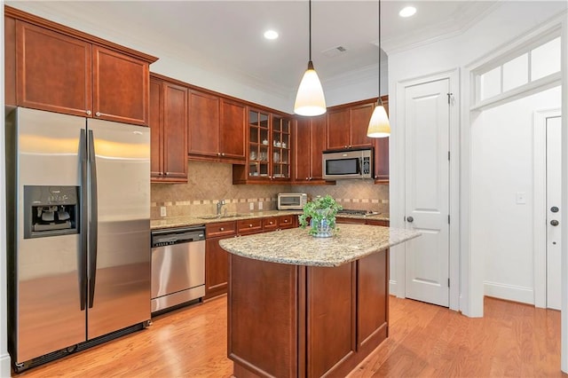 kitchen with decorative light fixtures, appliances with stainless steel finishes, tasteful backsplash, and light wood-type flooring