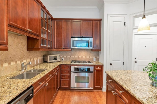 kitchen featuring sink, light hardwood / wood-style floors, hanging light fixtures, crown molding, and stainless steel appliances