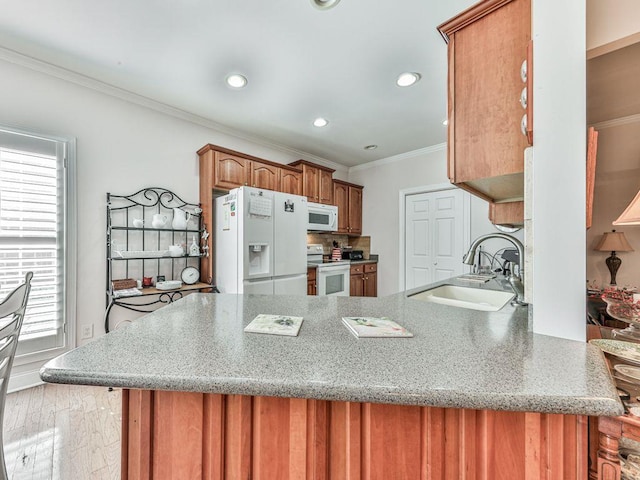 kitchen with sink, white appliances, light hardwood / wood-style flooring, and kitchen peninsula