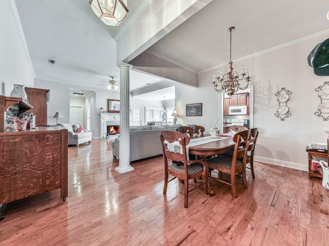 dining area with crown molding, ceiling fan with notable chandelier, hardwood / wood-style flooring, and ornate columns