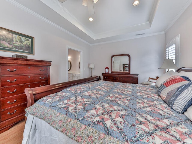 bedroom featuring crown molding, ceiling fan, ensuite bathroom, a tray ceiling, and light hardwood / wood-style floors