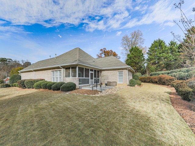 rear view of property featuring a sunroom, a patio area, and a lawn