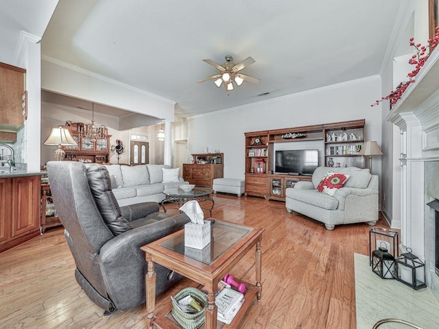 living room featuring decorative columns, ornamental molding, ceiling fan with notable chandelier, and light hardwood / wood-style floors