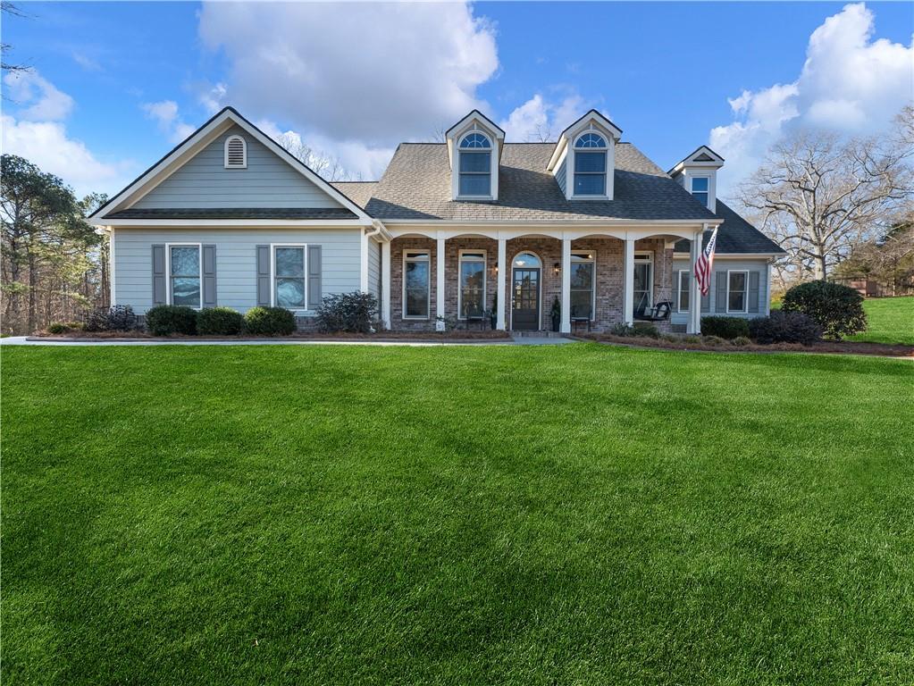 4248 Hog Mountain Rd, Hoschton, GA 30548 - cape cod-style house featuring covered porch and a front lawn