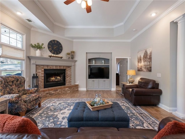 living room featuring ceiling fan, a fireplace, a tray ceiling, hardwood / wood-style flooring, and built in shelves