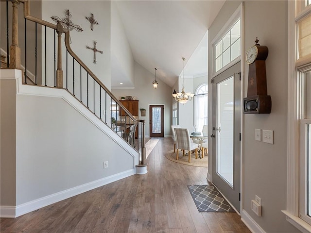 entrance foyer with high vaulted ceiling, a chandelier, and hardwood / wood-style floors